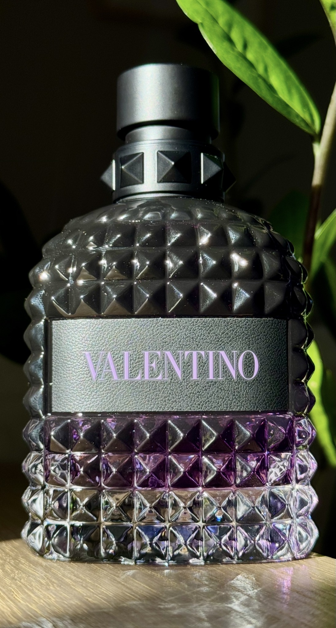 Studded violet fragrance bottle lit by low sunlight